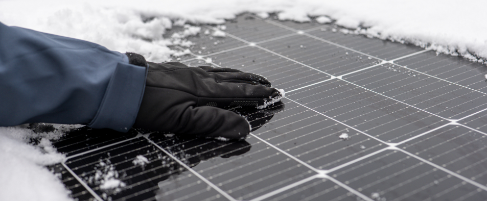 main qui enleve la neige sur un panneau solaire