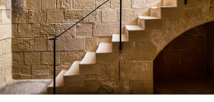 Escalier qui mene vers un sous sol avec des murs en pierre