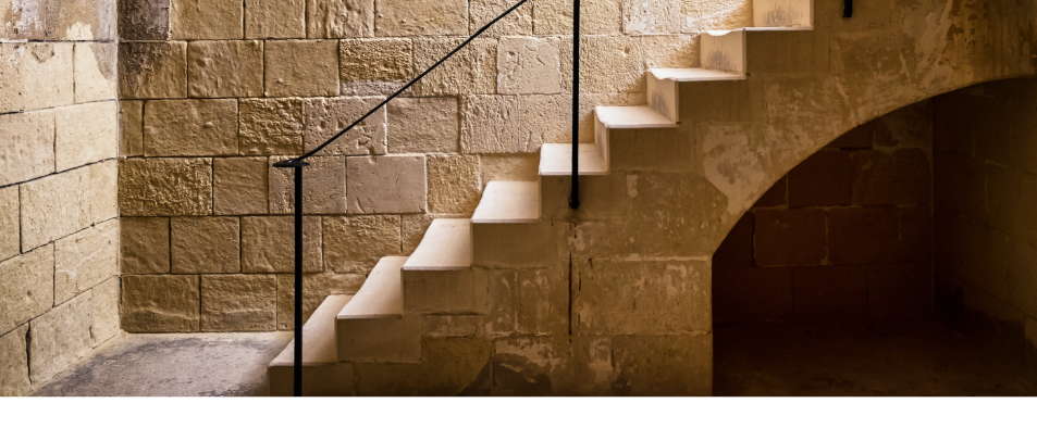 Escalier qui mene vers un sous sol avec des murs en pierre